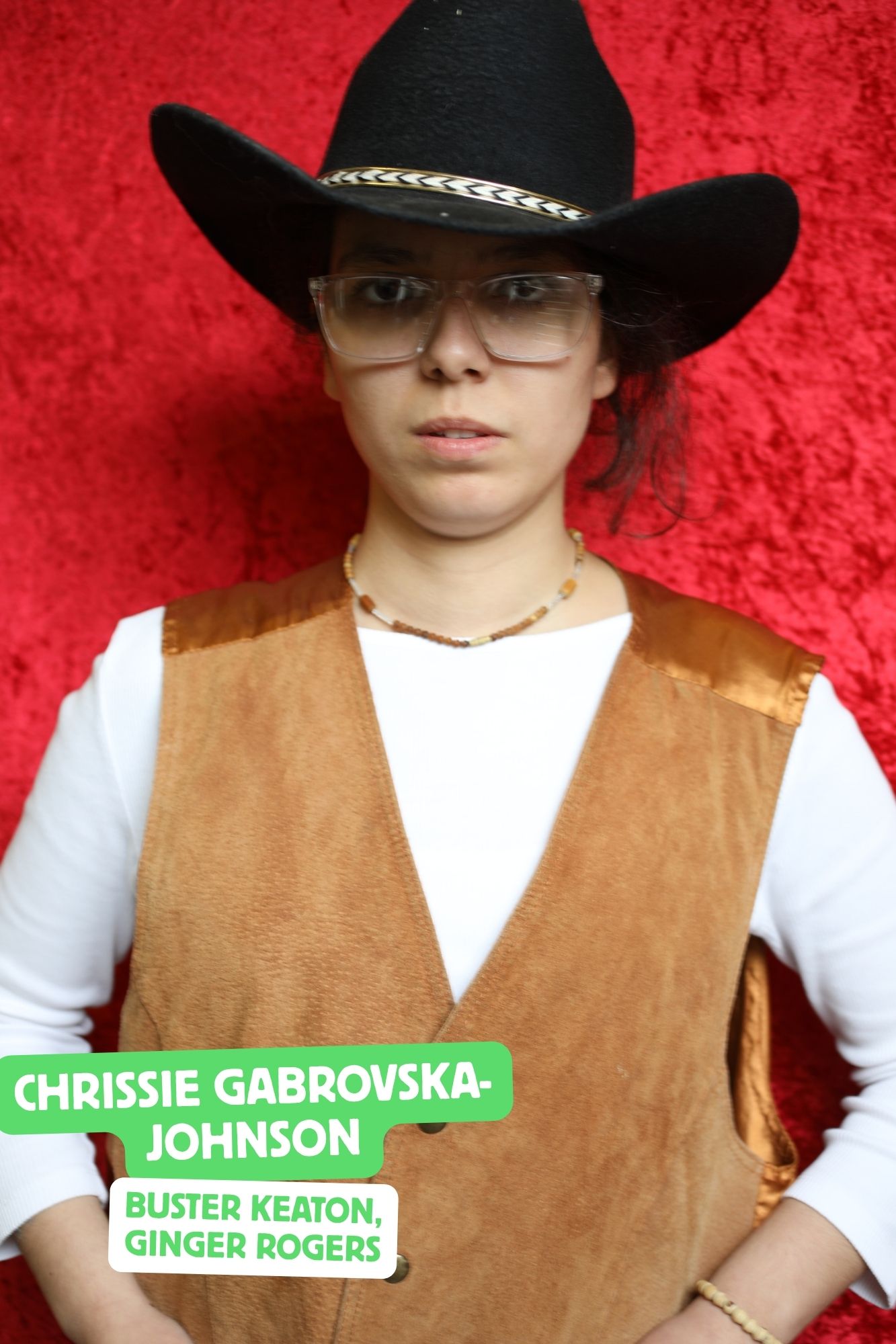Chrissie, a white woman with dark curly hair, is playing a cowboy. She is wearing a cowboy hat and waistcoat.